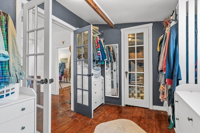 walk in closet with french doors, beam ceiling, and dark wood-type flooring