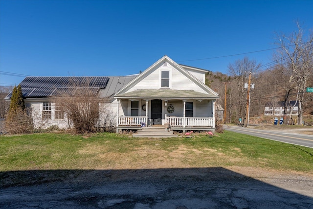view of front facade with a porch, a front yard, and solar panels