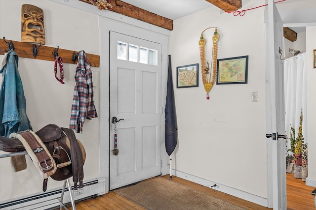 foyer entrance with a baseboard heating unit, beam ceiling, and hardwood / wood-style floors