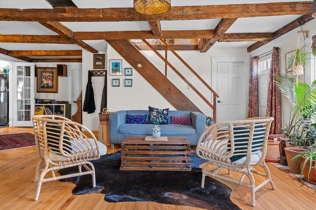 living area featuring hardwood / wood-style flooring, coffered ceiling, beamed ceiling, and stairway