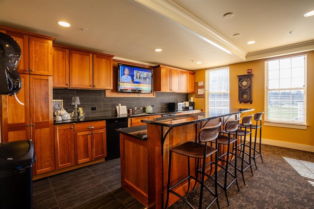 kitchen with backsplash, a kitchen island, baseboards, black dishwasher, and a breakfast bar area