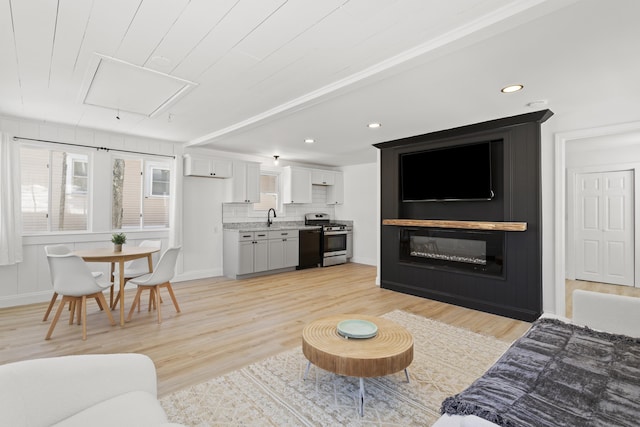 living room featuring light wood-type flooring, attic access, and recessed lighting