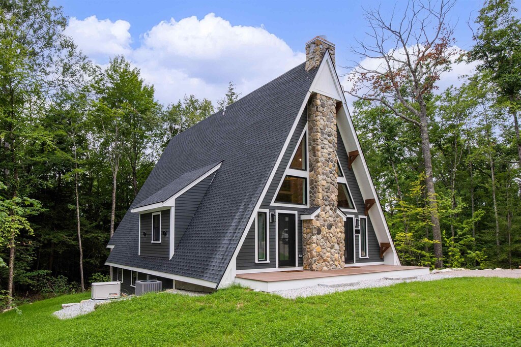 40 Huttwil Dr, Madison, NH 03849 - rear view of house with a lawn, roof with shingles, cooling unit, and stone siding