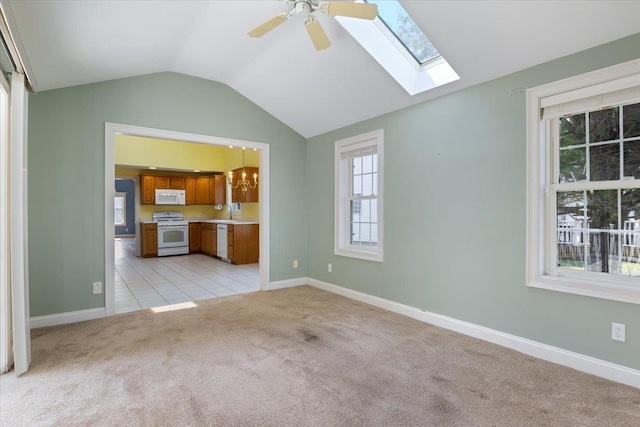 23 Hampton Mdws, Hampton, NH 03842 - unfurnished living room with light carpet, a sink, baseboards, vaulted ceiling with skylight, and ceiling fan with notable chandelier