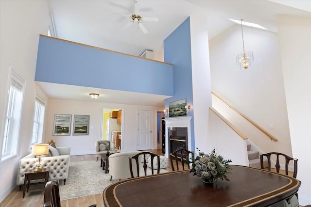 23 Hampton Mdws, Hampton, NH 03842 - dining space with high vaulted ceiling, stairway, wood finished floors, ceiling fan with notable chandelier, and a high end fireplace