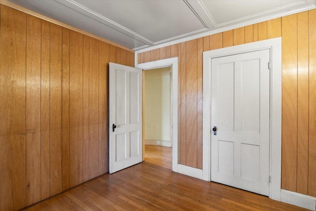 unfurnished bedroom featuring crown molding, wood finished floors, wood walls, and baseboards