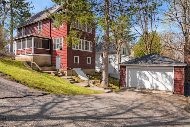 view of home's exterior with a detached garage, an outbuilding, a sunroom, and driveway