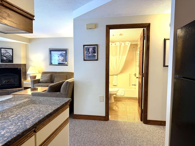 corridor featuring baseboards, a textured ceiling, and light colored carpet