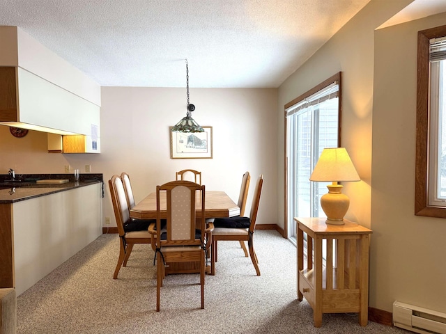 dining area featuring a baseboard heating unit, a textured ceiling, and light colored carpet