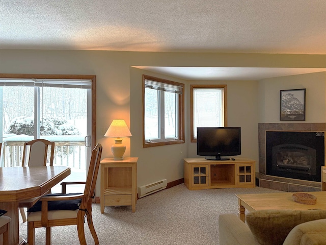 living area with baseboard heating, a healthy amount of sunlight, light colored carpet, and a fireplace