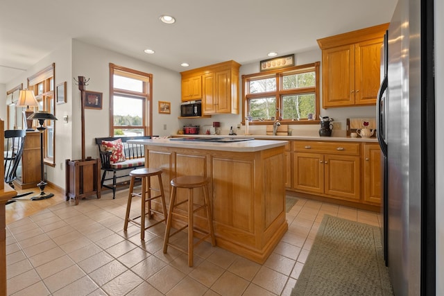 kitchen with light countertops, freestanding refrigerator, recessed lighting, and light tile patterned floors