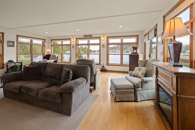 living room featuring recessed lighting, light wood-style floors, plenty of natural light, and a water view
