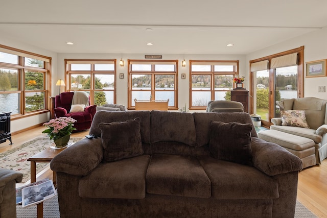 living room featuring light wood finished floors, recessed lighting, a water view, and a healthy amount of sunlight