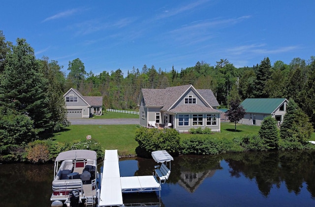 rear view of property with a lawn, a view of trees, a water view, and a garage