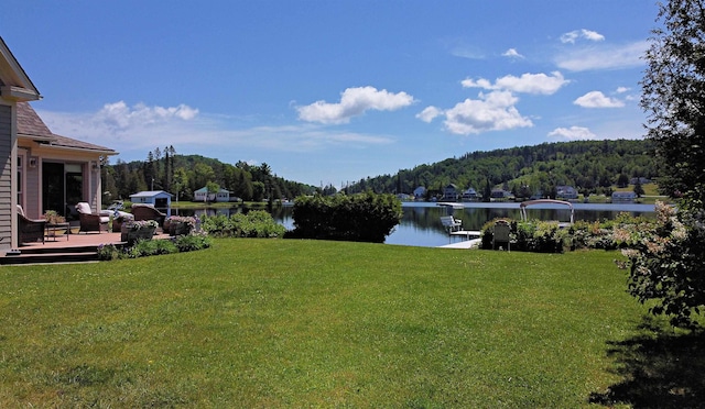 view of yard with a deck with water view and a wooded view