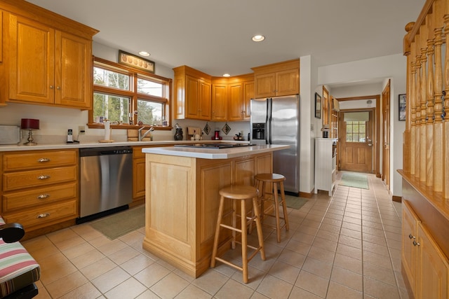 kitchen featuring stainless steel appliances, a center island, a kitchen breakfast bar, light countertops, and light tile patterned floors