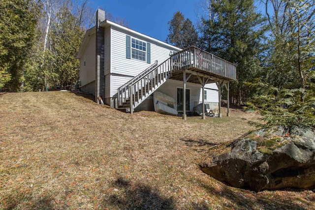 rear view of property with a wooden deck, a chimney, and stairs