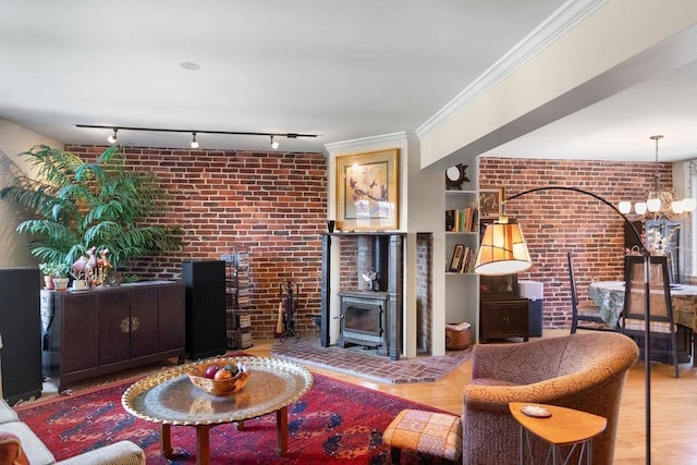 98 Hollis St, Manchester, NH 03101 - living room featuring wood finished floors, track lighting, brick wall, a wood stove, and a notable chandelier