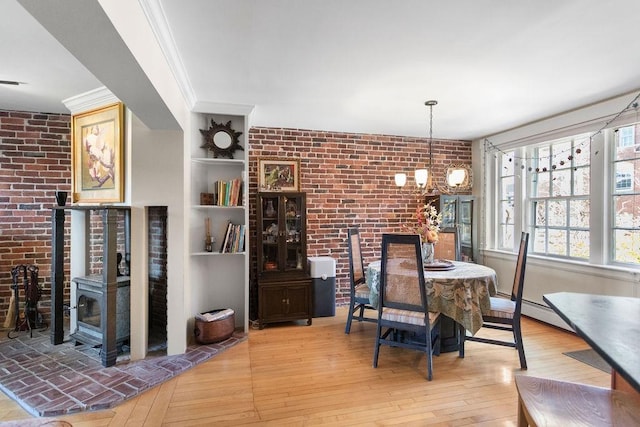 98 Hollis St, Manchester, NH 03101 - dining room with a healthy amount of sunlight, a notable chandelier, brick wall, hardwood / wood-style floors, and a wood stove