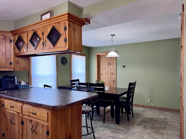 14 Summer St, Northumberland, NH 03582 - kitchen featuring dark countertops, a kitchen breakfast bar, a textured ceiling, and brown cabinets