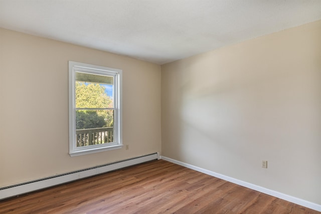 empty room with a baseboard radiator, baseboards, and wood finished floors