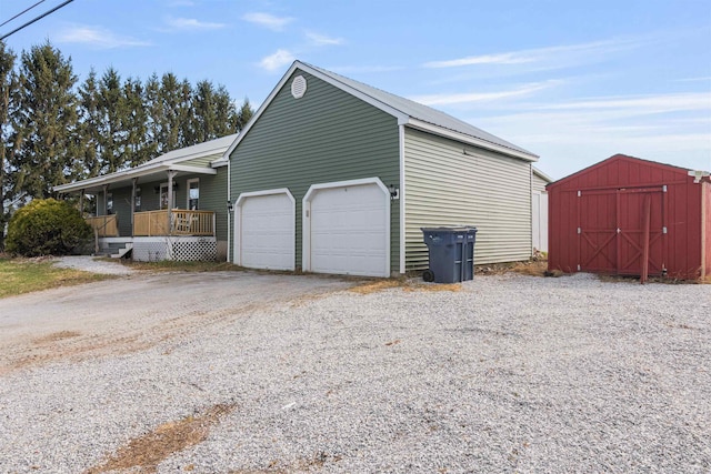 view of property exterior with a shed, driveway, an outdoor structure, a porch, and a garage