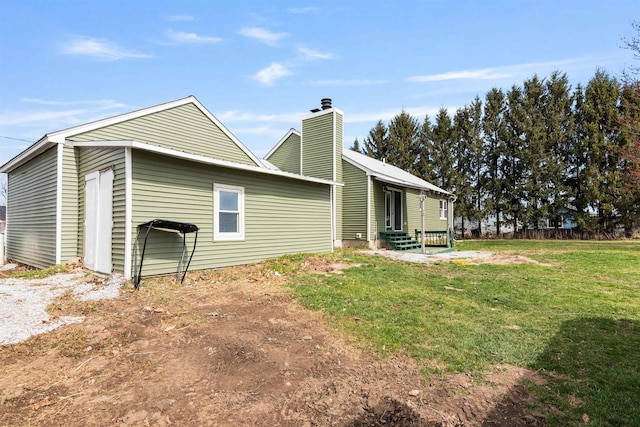rear view of property featuring a chimney and a yard