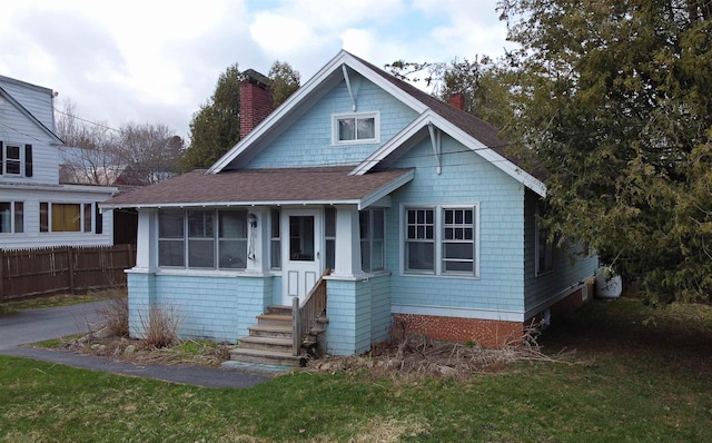 view of front of property featuring a chimney, roof with shingles, and fence