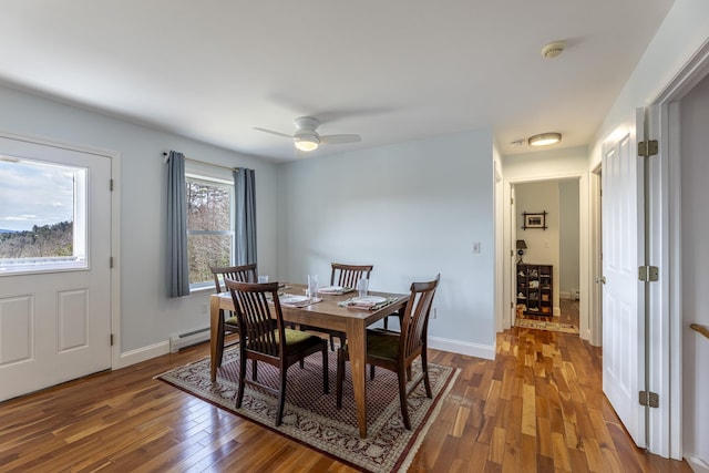 dining area with a baseboard heating unit, wood finished floors, a ceiling fan, and baseboards