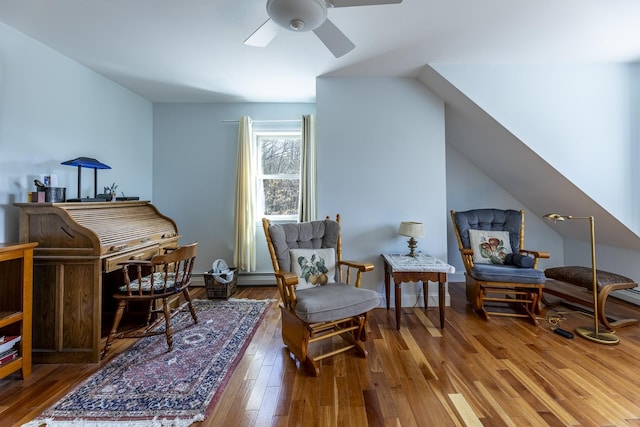living area with hardwood / wood-style flooring, ceiling fan, and baseboard heating