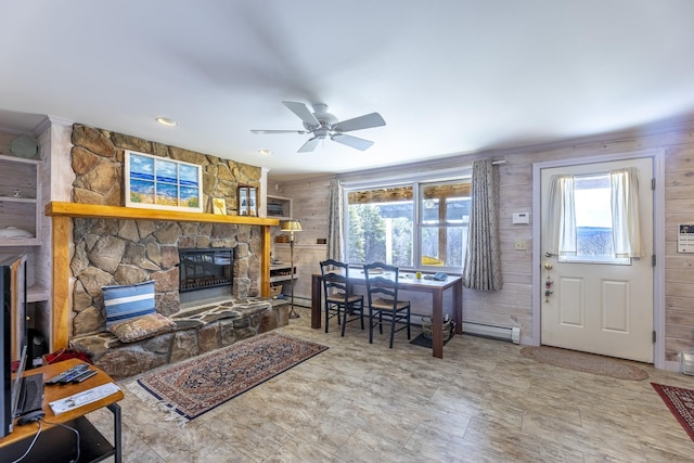 living room with plenty of natural light, wood walls, a fireplace, and ceiling fan