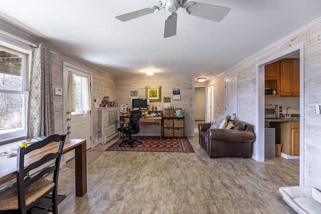 office space with ornamental molding, a sink, light wood-type flooring, baseboard heating, and ceiling fan