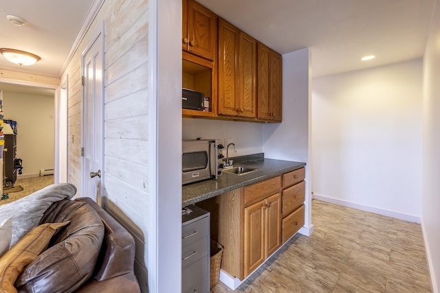 kitchen featuring a sink, dark countertops, baseboards, recessed lighting, and brown cabinets