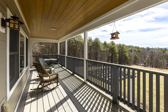 wooden terrace with a view of trees and covered porch