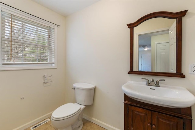 half bath with toilet, vanity, baseboards, tile patterned flooring, and visible vents