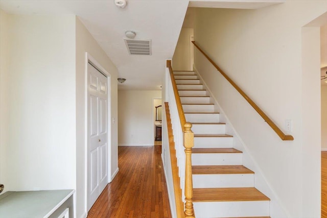 stairway with baseboards, wood finished floors, and visible vents