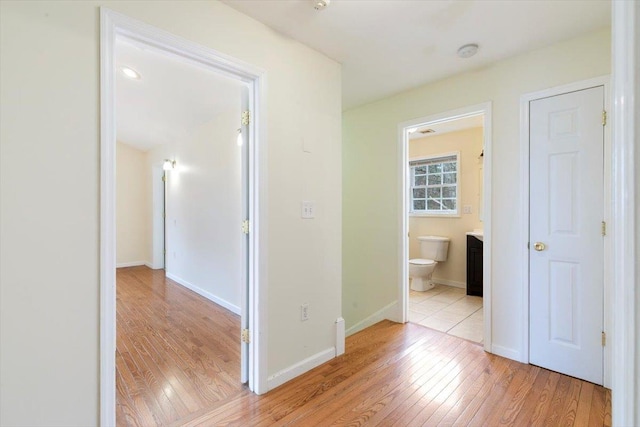 corridor featuring baseboards and light wood-type flooring