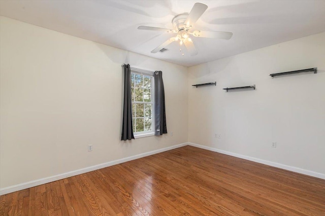 unfurnished room with wood finished floors, visible vents, a ceiling fan, and baseboards