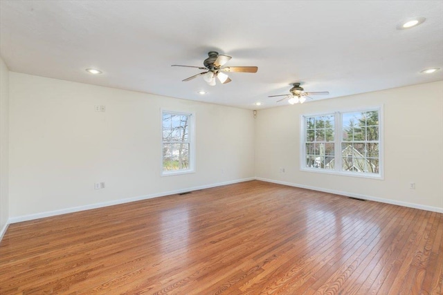 empty room featuring light wood-type flooring, plenty of natural light, baseboards, and ceiling fan
