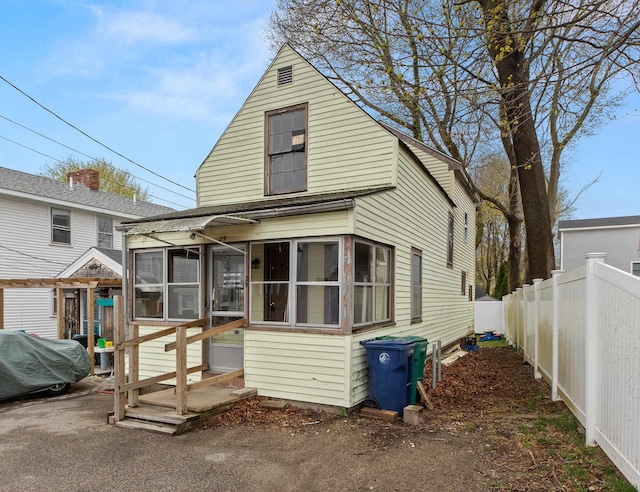 rear view of house with a sunroom and fence