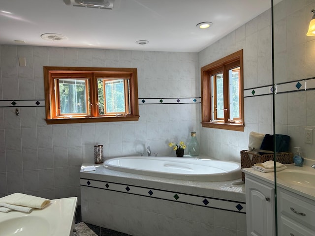 full bath with tile walls, a garden tub, and vanity