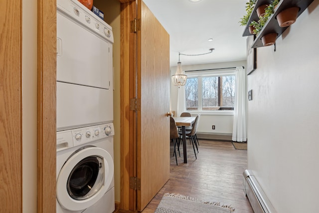 washroom featuring a notable chandelier, wood finished floors, stacked washer and clothes dryer, laundry area, and a baseboard radiator