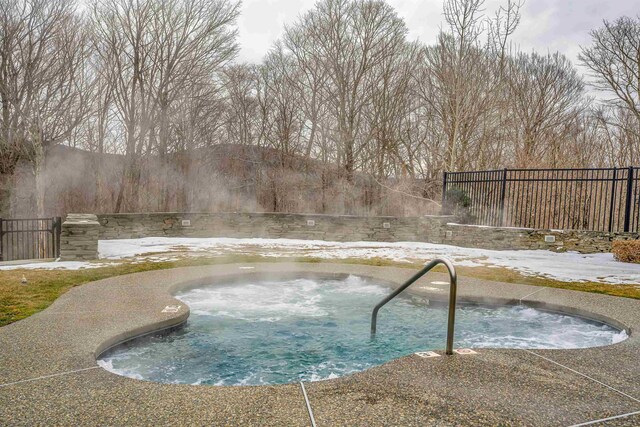 view of pool featuring an in ground hot tub and fence