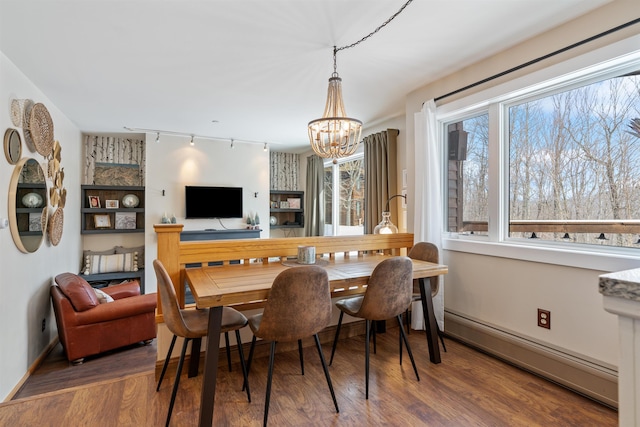 dining area featuring a baseboard heating unit, baseboards, an inviting chandelier, wood finished floors, and rail lighting