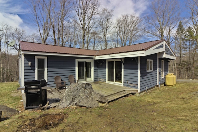 rear view of property with a wooden deck, a yard, and metal roof