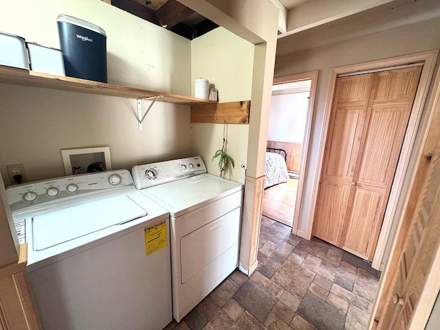 laundry room with washing machine and dryer, stone tile floors, and laundry area