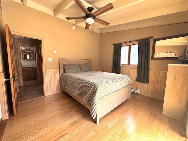 bedroom featuring wainscoting, baseboard heating, wooden walls, and light wood finished floors