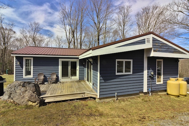 rear view of property with a lawn, a wooden deck, and metal roof