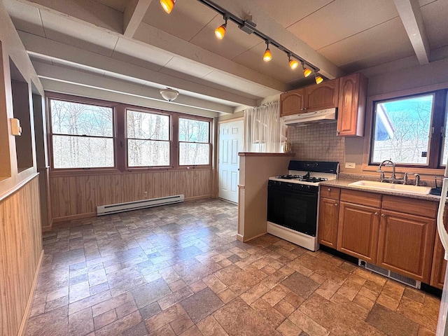 kitchen with a sink, plenty of natural light, gas range, baseboard heating, and under cabinet range hood