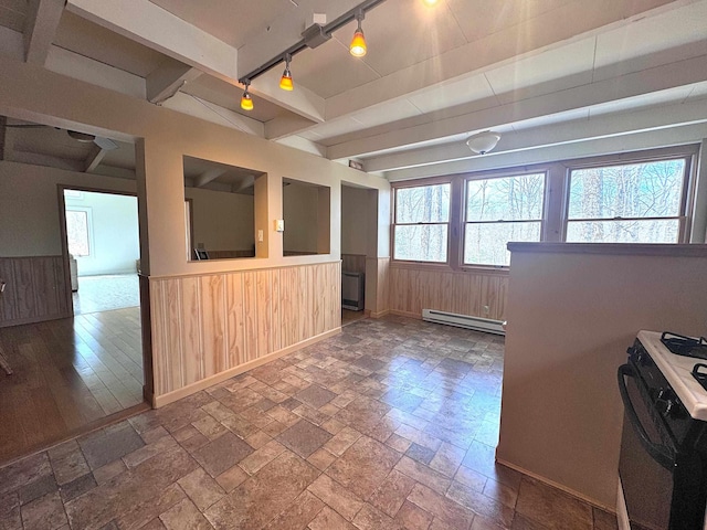 kitchen featuring a baseboard heating unit, wainscoting, stone tile floors, wood walls, and black range with gas cooktop